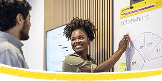 Dos compañeros de trabajo utilizan el Bloc de reuniones Post-it® durante su charla
